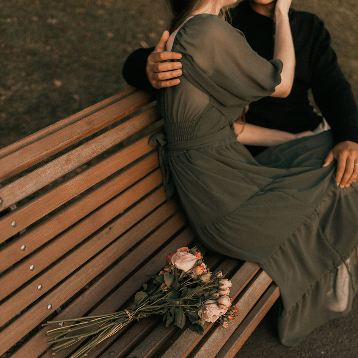 A couple sitting on a bench caressing